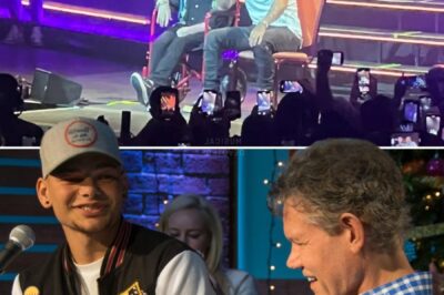 Kane Brown left the crowd in awe when he delivered the surprise of a lifetime, stepping back from the mic to reveal none other than country legend Randy Travis go onstage in his red wheelchair. The audience froze for a heartbeat, then erupted in cheers that shook the arena. As the two began a heartfelt duet of “Three Wooden Crosses,” the air seemed to thicken with emotion. Randy’s voice, though weathered, carried a weight of history, blending perfectly with Kane’s smooth tones. Tears glistened in the eyes of fans as the moment unfolded—a bridge between generations, a tribute to country music’s soul, and a memory etched forever in their hearts.